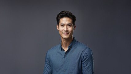 Obraz premium Confident and charismatic Korean man with a warm smile and natural beauty. Brunette hair and flawless skin complement his captivating gaze. Studio shot with copy space, perfect for beauty and fashion