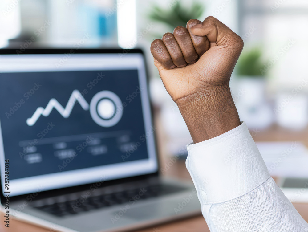 Poster a determined hand fist pumping in celebration over successful business analytics displayed on a lapt