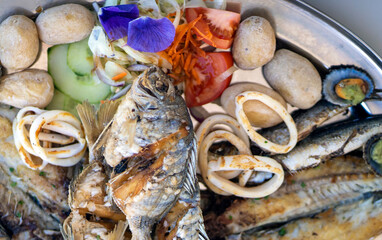 A grilled fish mix plate with various types of fish, seafood, scallops and squid rings.