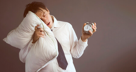 A young funny man in a white shirt and tie with disheveled hair slept through the deadline, holding...