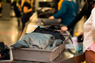 A woman is passing the checkpoint in the airport with bags.