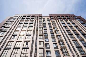 A low-angle shot of a modern apartment building on a sunny day under a blue sky.