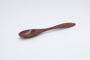 Single dark brown wooden spoon on white background.