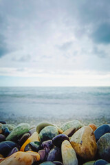 Beautiful Abstract background with pebbles - round sea stones against blue sky. Vertical photo.