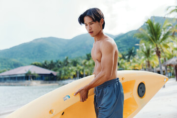 Happy Asian Man Kayaking in Tropical Summer Vacation: A Thrilling Adventure on a Beach with Palm...