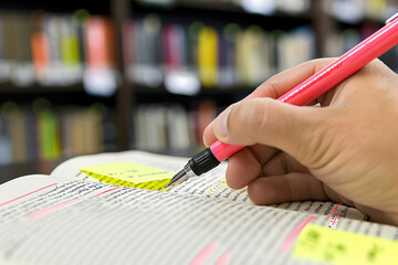 Editor marking corrections on printed manuscript, red pen and post-it notes in hand.