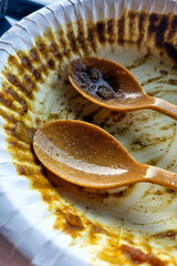The table shows remnants of food and used utensils. Empty single-use plates and plastic cutlery - post-meal cleanup reveals disposable tableware and dining waste.