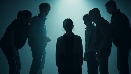 Teenagers bullying sad girl on stage with blue backlight