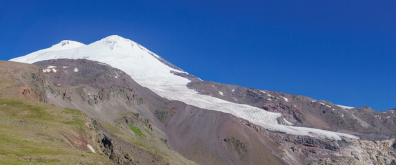 view of the double top of Mount Elbrus and the glacier flowing down from them into the valley