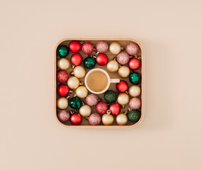 Creative Christmas layout made with colorful Xmas baubles and cup of coffee on pastel cream background. Minimal Christmas and New Year concept. Trendy coffee idea. Festive holiday flat lay.