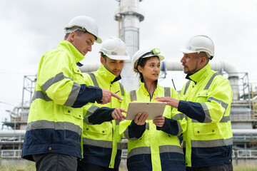 Diverse group of petrochemical engineers looking at on tablet and discussing inspection and...