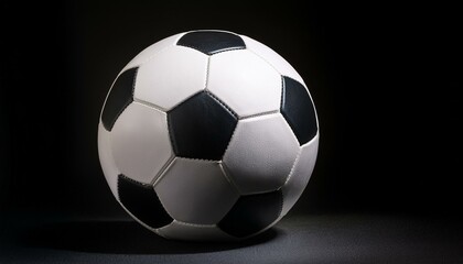 Naklejka premium A black and white soccer ball sits on a black background