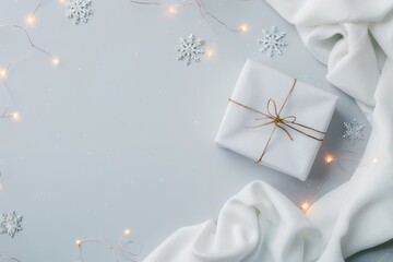 A white wrapped gift sits on a light gray background surrounded by white fabric, twinkle lights, and snowflakes.