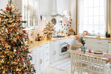 Cozy scandinavian kitchen decorated for Christmas with white cabinets, wooden countertops, and a dining table adorned with Christmas trees, ornaments, and a pie, enhancing the holiday spirit