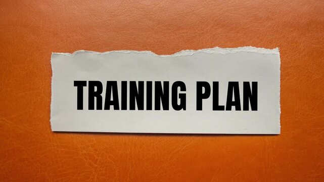 Training plan message writing on ripped torn paper on brown background. Conceptual training plan symbol.
