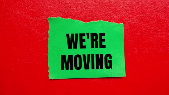 We are moving message writing on ripped torn green paper on red background. Conceptual we are moving symbol.