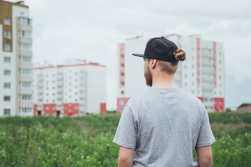 A man looks at the new buildings outside the city near the field.