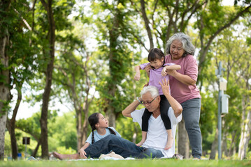 Fototapeta premium Happy Asian family children having fun and playing with her grandparents in the park