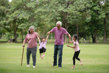Fototapeta premium Happy Asian family children having fun and playing with her grandparents in the park