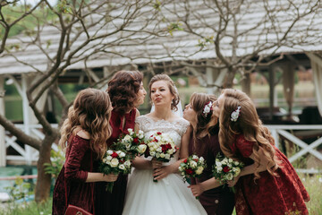 A bride and her bridesmaids are posing for a picture in front of a bridge. The bride is wearing a...