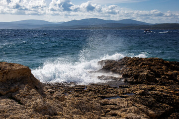 Splashing waves blue cloudy sky and aegean sea in a sunny windy day, nature's symphony