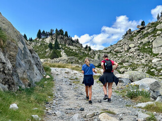 Fototapeta premium A mother and daughter hike along a rocky path near Amitges Refuge in the Catalan Pyrenees.