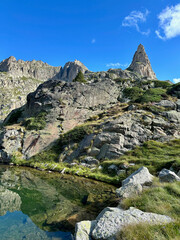 Mountain peaks near Amitges Refuge are mirrored in a crystal-clear lake, with a vibrant blue sky overhead.