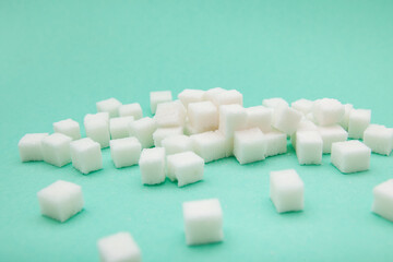 Sweet white sugar cubes on light green background, card with sucrose