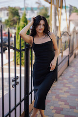 Sexy attractive lady posing in the black dress in a city