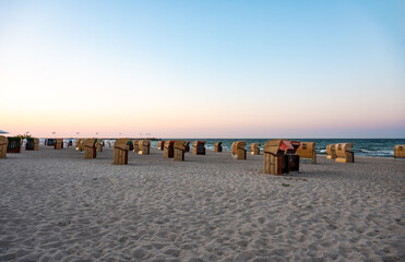 Obraz premium Dahme, Germany - Sunset over the beach with beach baskets or Strandkörbe