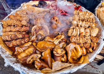 Hot street food made from fried pork in the form of kebabs, various sausages and smoked pork skin closeup.	