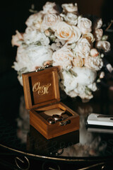 A wooden box with the initials C and M on it sits on a table next to a bouquet of flowers