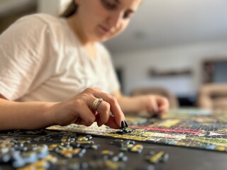 Teenage caucasian girl in white shirt solving puzzle in her home