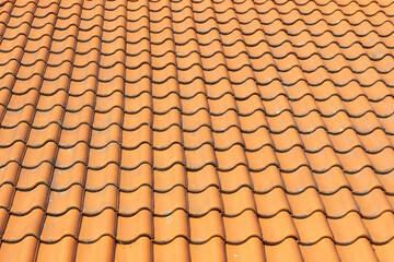 Orange tiled roof with traditional clay roofing tiles. Detailed pattern and texture in residential architecture. Terracotta tiles background. Structure and design of the roof.