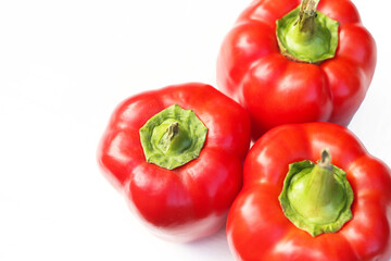 Red bell peppers isolated on a white. Empty copy space food bacground. Homegrown in a backyard garden vegetables. Fresh and organic food. Healthy eating and sustainable living. Shiny paprika.