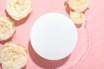 Beautiful rose flowers and round shaped podium in water on pink background, flat lay