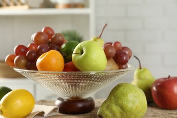 Glass vase with different fresh fruits on table, closeup