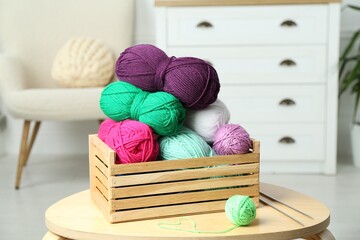 Wooden crate with different yarns on coffee table indoors