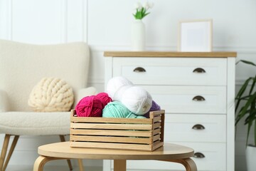 Wooden crate with different yarns on coffee table indoors