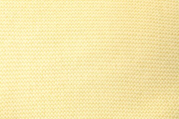 Fototapeta premium Texture of light yellow knitted fabric as background, top view