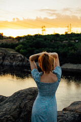 young girl in blue dress in field at sunset. girl with loose hair.