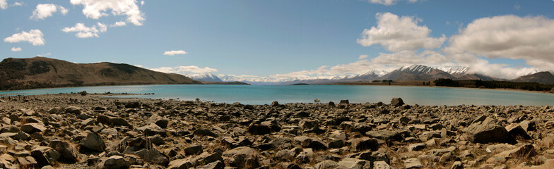 panorama of a scenic view of a lake with mountains and snow at sunset