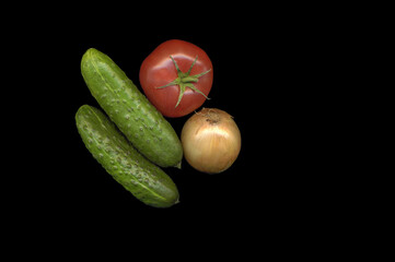 still life of vegetables on a black background (cucumbers, tomato and onion)