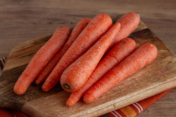 fresh carrots on a chopping board, wooden table, raw carrots, no people,