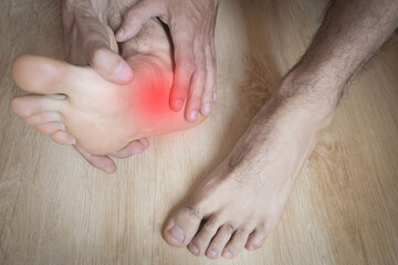 A close-up of a man massaging,examining, stretching his painful foot. Injured. High-angle shot.