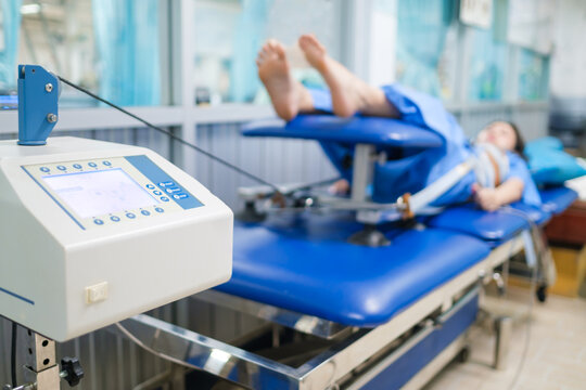 Mechanical traction or decompression tension on the spine, taking pressure off the joints and discs of the spine giving pain relief. Physical therapy technology machine with paint in the background.
