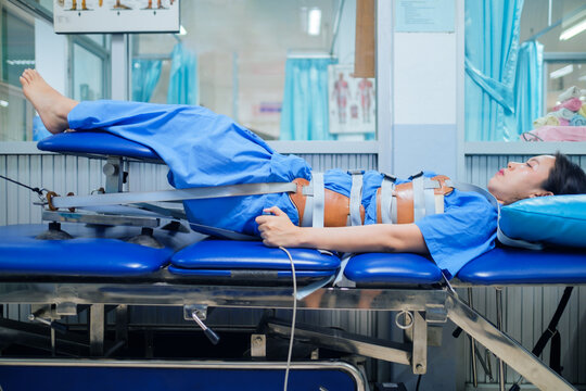 Patient lying on a Mechanical traction bed, decompression of the tension on the spine, taking pressure off the joints and discs of the spain giving pain relief. Physical therapy healthcare technology.