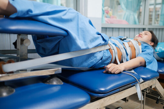 Patient lying on a Mechanical traction physio bed with belt strapped around the body, decompression of the tension taking pressure of the joints and spine pain relief. Physical therapy technology.