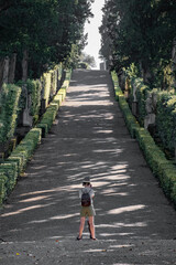Uphill dirt road with cypress trees on the sides with people taking photographs
