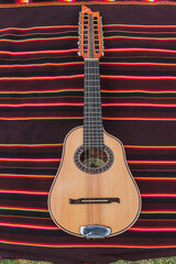 Fototapeta premium Traditional Andean instruments elegantly arranged on a striped textile. The Charango, Mandolin, and Bandolina are artfully crossed, highlighting their fine details and cultural significance.